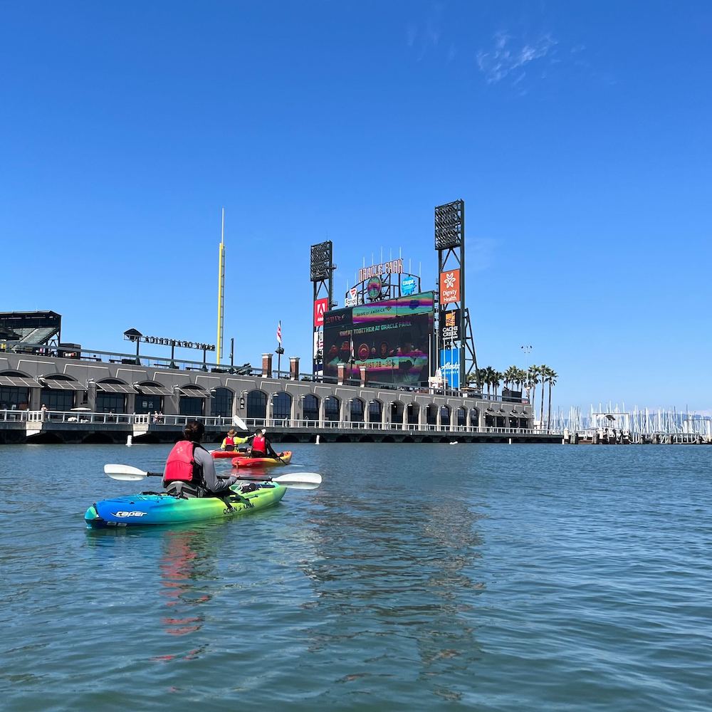 The Capsule team kayaking together on a sunny day by the ballpark in San Fransisco.